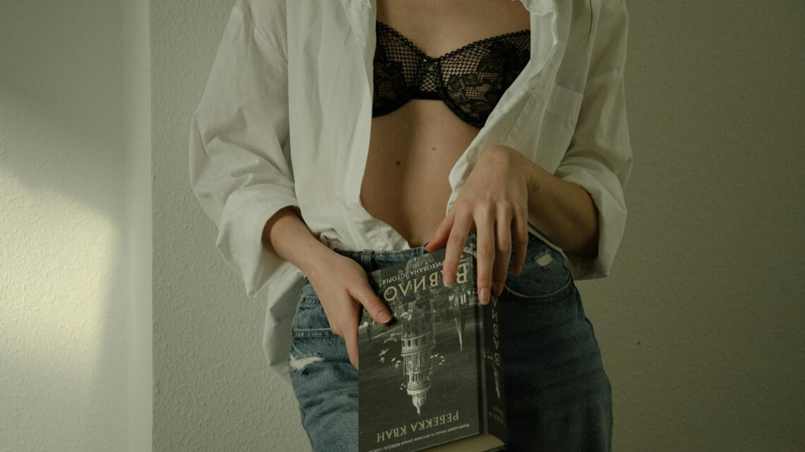 A woman in a bra and jeans holding a book
