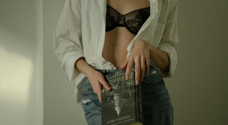 A woman in a bra and jeans holding a book