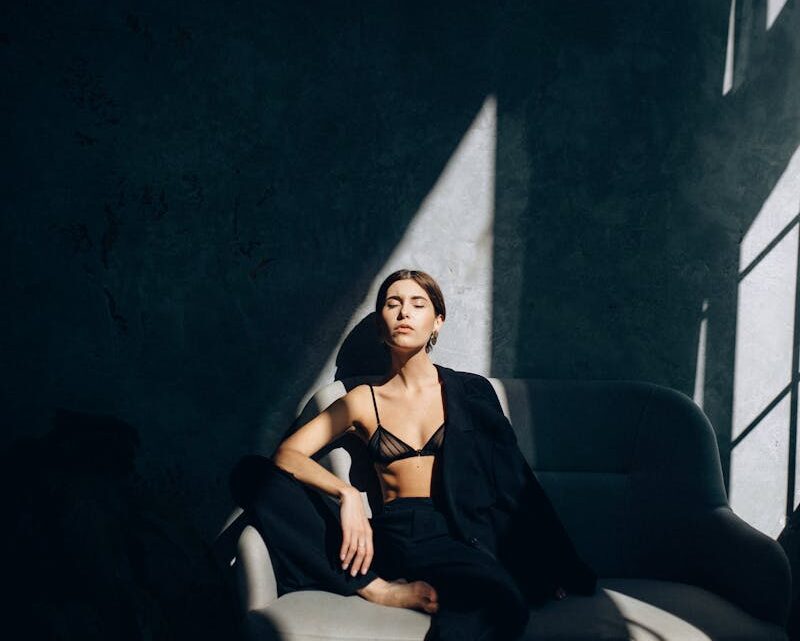 Model in Black Chiffon Bra and Pants Sitting on the Sofa with a Blazer Draped over Her Shoulder